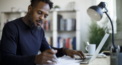 An adult man working at home in front of his laptop.
