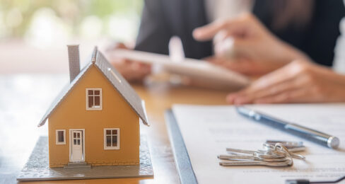 House model with an agent and customer in the background discussing contract to buy.