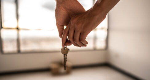 A couple holding hands while holding a key to their new rental.