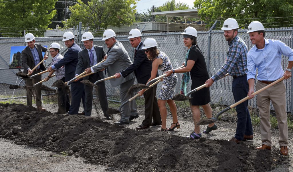 Development partners hold up shovels of dirt at a groundbreaking ceremony.