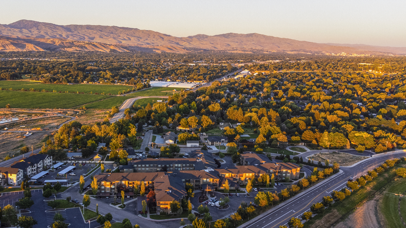 An aerial view of residential buildings in Boise, Idaho with hills reflecting the sunset in the background.