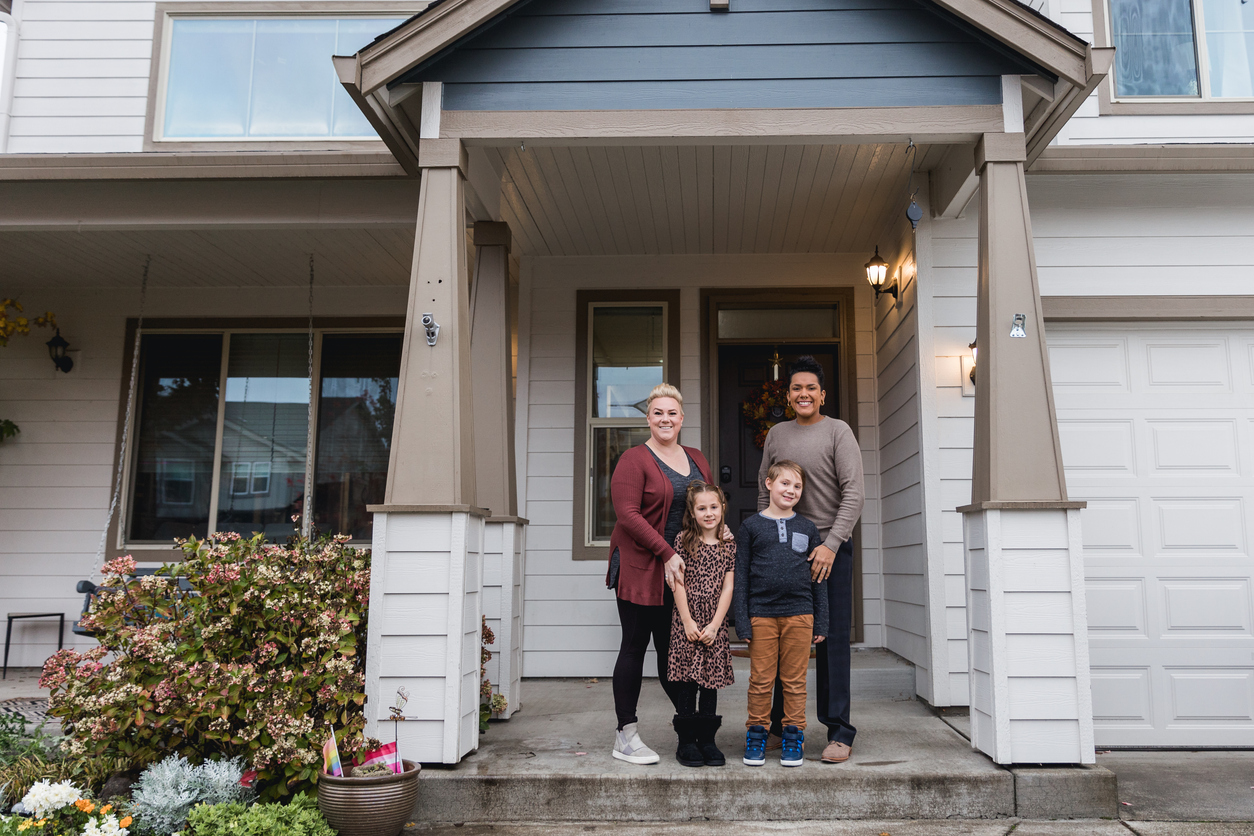 A family of four standing outside of their home.