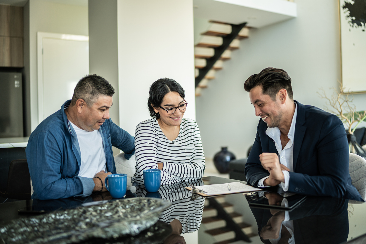 A financial advisor meeting with a mid adult couple in their home.