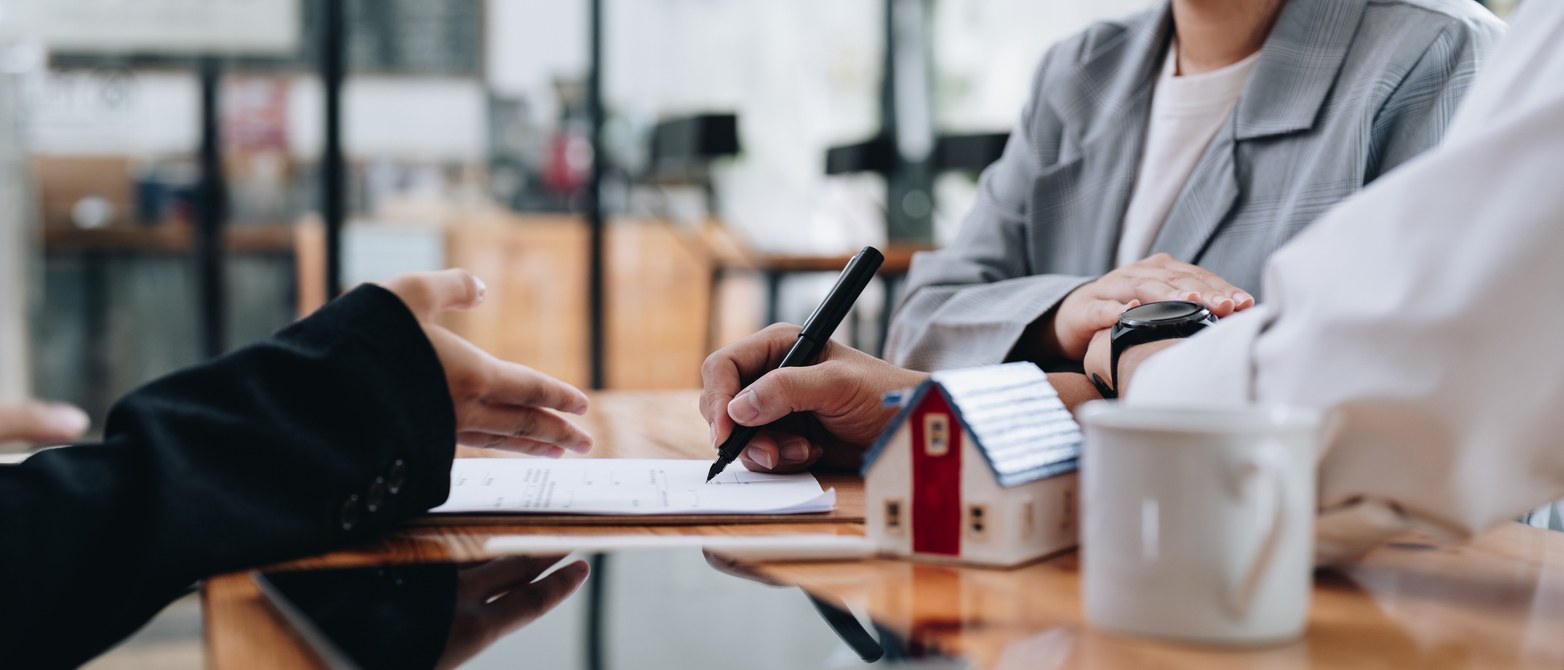 A mortgage lender meets with a couple who are signing papers for their home loan.