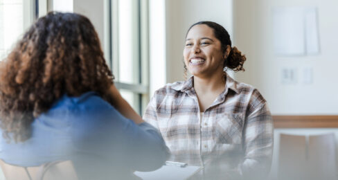 A young woman smiles as she talks to a job coach.