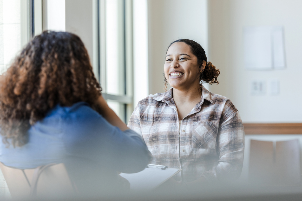A young woman smiles as she talks to a job coach.