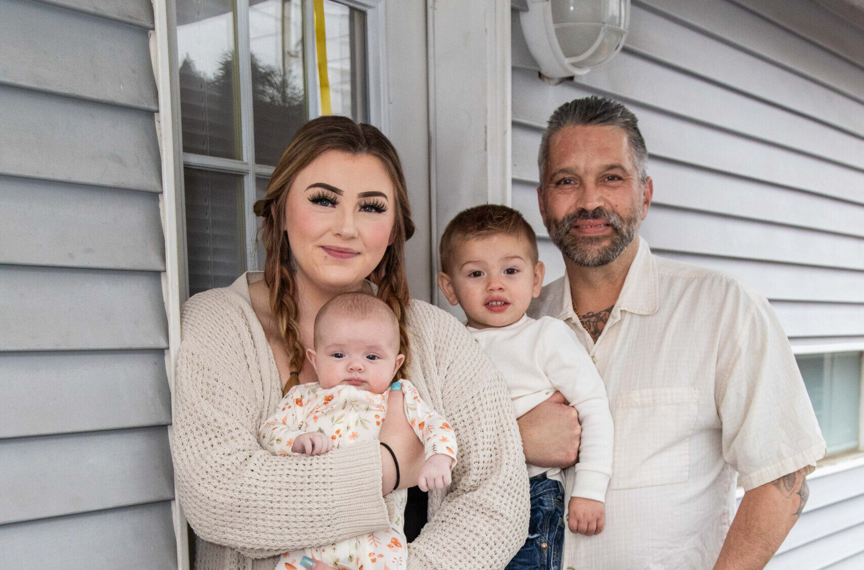 Couple with young children standing on front porch.