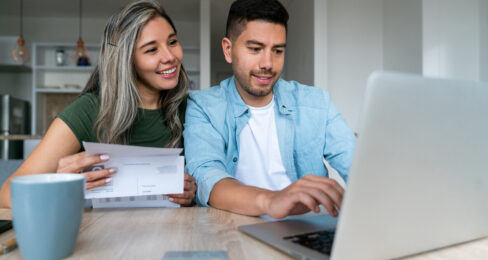 Happy couple at home paying bills online