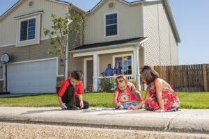 Children drawing on a sidewalk in from of their home.